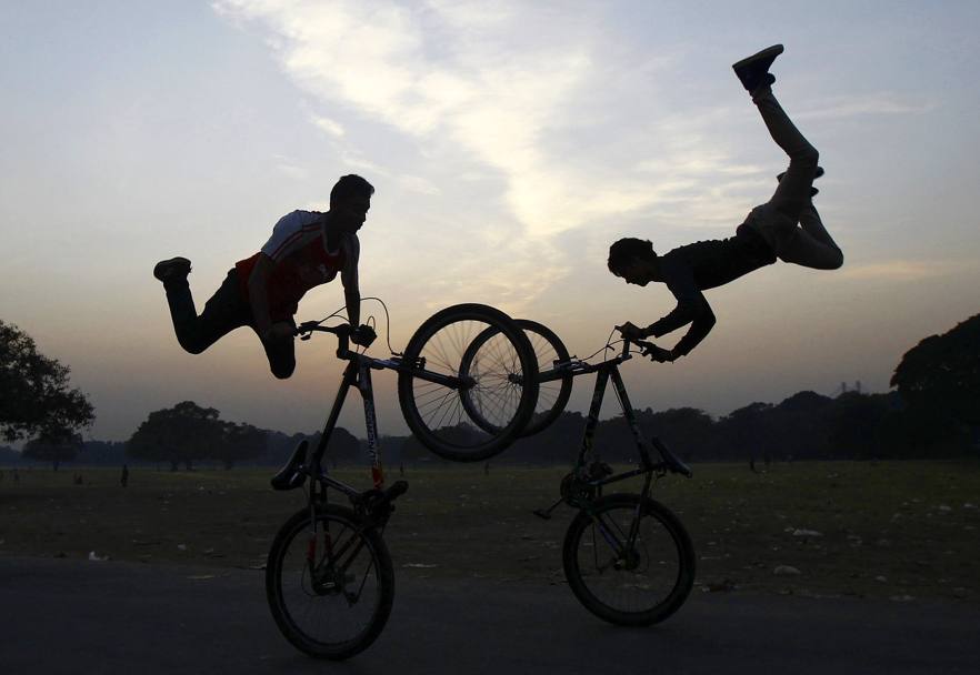 India. Acrobati della bicicletta si esibiscono al tramonto durante lo 